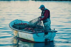 Fisherman hauling lobster traps in a tranquil bay at sunset while preparing for the evening catch photo