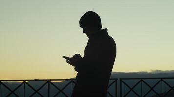 Silhouette Of A Man Scrolling The News On The Phone At Sunset photo