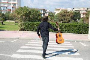 Young Man Plays Guitar On Pedestrian Crossings Of A Street In Summer Season photo