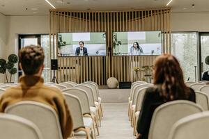 Back View Of Audience In The Modern Conference Hall Or Seminar Meeting With Large Media Screen Showing Presentation Of Business photo