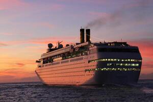 A large cruise ship sails on the open ocean during a stunning sunset. photo