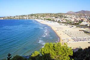 A picturesque aerial view of a Mediterranean coastal town with a sandy beach lined with umbrellas. photo