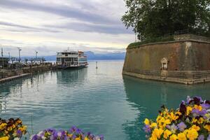 A ferry docked at a historic stone fortress on a turquoise lake. photo