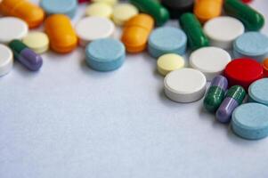 Side view of variety of colorful pills and capsules scattered on a light colored surface with customizable space for text. photo