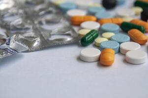 Variety of colorful pills and capsules scattered on a light colored surface with customizable space for text. photo