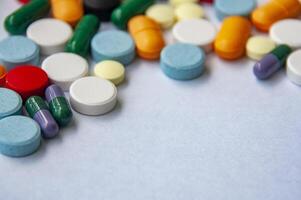 Top view of colorful pills and capsules scattered on a light colored surface with customizable space for tex. photo