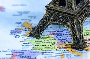 Closed up of miniature Eiffel Tower placed on a world map. Travel destination concept photo