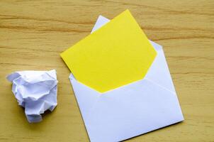Top view of empty yellow notepad inside an envelope with crumpled paper with customizable space for text photo