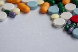 Colorful pills and capsules scattered on white cover background with customizable space for text photo