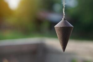 Plumb bob, plummet or conical iron hung with rope for measurement level, use for determining perpendicularity . Concept work tool for construction and carpentry. photo