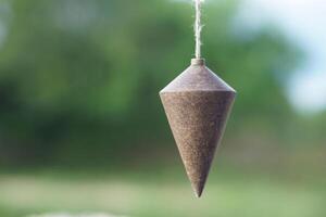 Plumb bob, plummet or conical iron hanging with rope for measurement level, use for determining perpendicularity . Concept, work tool for construction and carpentry. photo