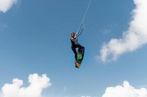 Girl-kayv d jump makes a trick with a grab against the background of a blue sky and clouds photo