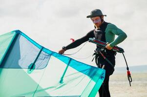 A male kitesurfer unwinds and straightens the lines of her kite before riding. Preparing the kite for kitesurfing photo
