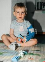 Young Child with Arm Cast Playing with Building Blocks photo