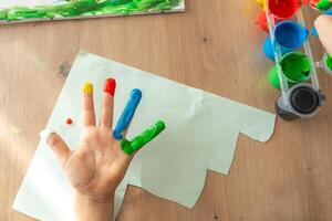Children's fingers stained with paint, each color on a different finger, open palm of a child 4-5 years old photo above