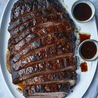 A platter of ribs with sauce and two bowls photo