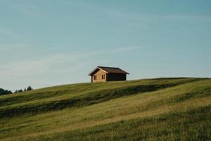 Tranquil wooden chalet nestled on a grassy hilltop under a clear sky photo