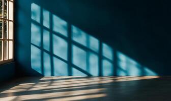 Sunlight casts shadows on a teal wall through a window photo