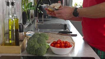 Man spreads cream cheese on bagel at modern kitchen counter. Close-up of male hands preparing bagel sandwich with cream cheese during breakfast. Healthy morning meal preparation at home video