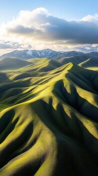 The sun is shining on a green hill with mountains in the background photo