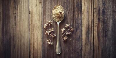Psyllium husk on a spoon with dried flowers on wood photo