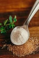 Psyllium powder and seeds in a spoon on wooden surface photo