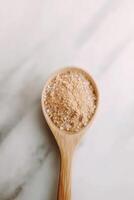 Psyllium husk in a wooden spoon on a marble surface photo