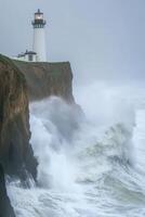 Waves hit cliffs by lighthouse in a storm photo