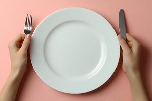 Minimalist Dining Concept with White Plate, Fork, and Knife on Pink Background photo