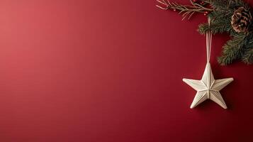 star ornament hanging on deep red background with pine branches photo