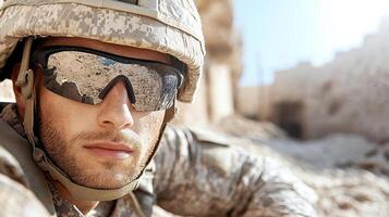 soldier in tactical gear with sunglasses, focused and alert in desert environment photo