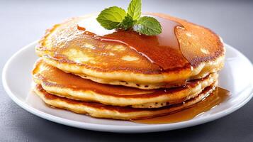 Freshly made pancakes stacked with syrup and mint garnish, deliciously inviting photo