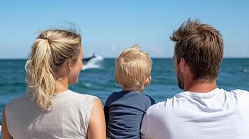 family enjoying day at beach, watching dolphins play in distance photo