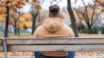 person sitting on bench in park surrounded by autumn leaves, feeling contemplative photo
