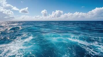 Vibrant ocean waves under clear blue sky with fluffy clouds photo