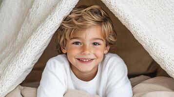 Cozy child smiling under blanket fort, enjoying story moment photo