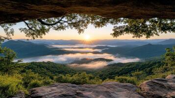 The sun rises over the mountains from a cave photo