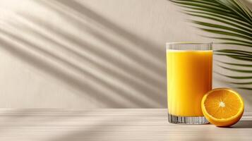 Orange juice in glass with palm leaves on wooden table photo