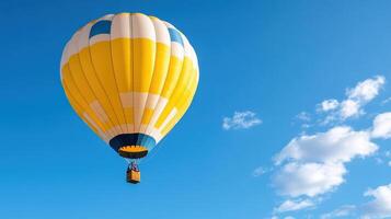 A yellow and white hot air balloon is flying in the sky photo