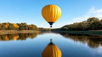 A yellow hot air balloon floating over a river photo