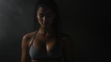fit woman in sports bra, showcasing her toned physique in low light photo
