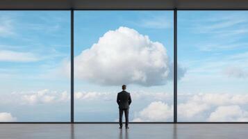 business leader standing at panoramic office window, gazing at clouds photo