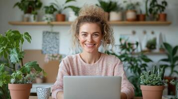 woman working in flexible office space surrounded by plants, smiling happily photo