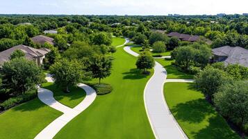 Aerial view of lush suburban neighborhood with winding paths and green lawns, showcasing photo