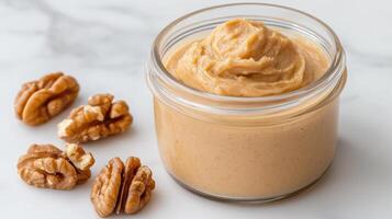 Creamy walnut butter in glass jar with walnuts nearby creates delightful scene photo