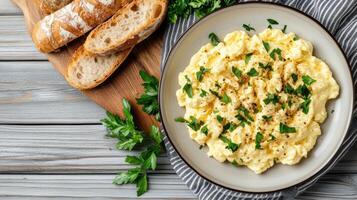 Creamy scrambled eggs garnished with fresh herbs, served with crusty bread photo