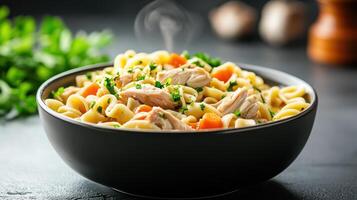 steaming bowl of homemade chicken noodle soup with fresh herbs and vegetables photo
