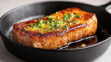 thick cut of pork chop sizzling in skillet, topped with herb butter, exuding delicious aromas photo