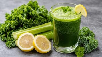 Fresh green detox juice with lemon and kale, surrounded by fresh ingredients, is refreshing and photo