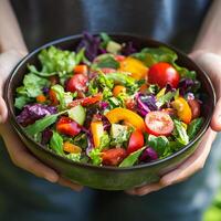 Colorful organic salad held by person in outdoor setting during sunny day photo